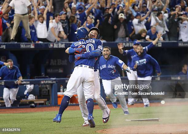 Josh Donaldson of the Toronto Blue Jays is congratulated by Troy Tulowitzki after scoring the game-winning run in the tenth inning during MLB game...
