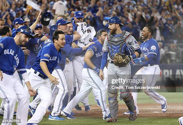 Jonathan Lucroy of the Texas Rangers walks off the field as Toronto Blue Jays players celebrate their victory in the tenth inning during MLB game in...