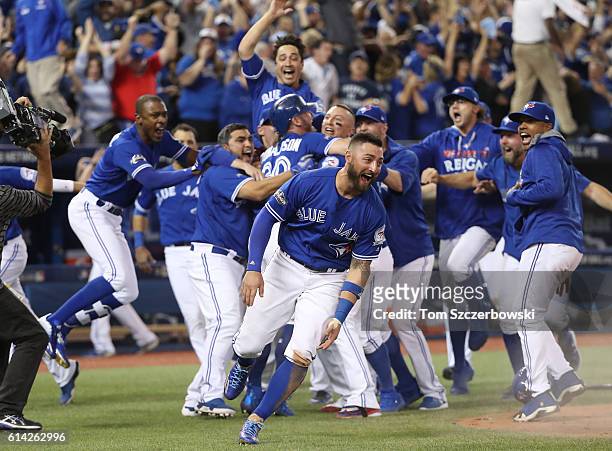 Josh Donaldson of the Toronto Blue Jays is congratulated by Troy Tulowitzki after scoring the game-winning run as Kevin Pillar runs while celebrating...