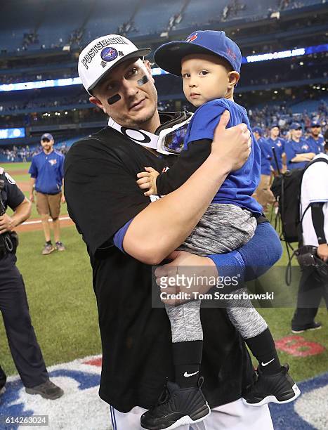 Troy Tulowitzki of the Toronto Blue Jays celebrates their series victory as he holds his son Taz Tulowitzki on the field following their MLB game...