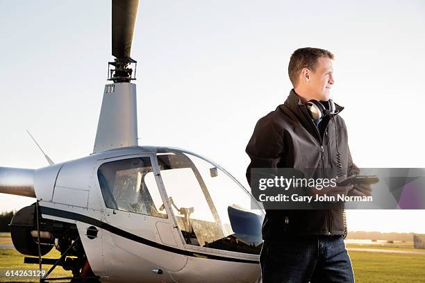 proud pilot standing by his helicopter - pilot jacket stock-fotos und bilder