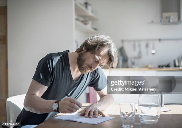 portrait of bearded man sitting at home - belastingen stockfoto's en -beelden