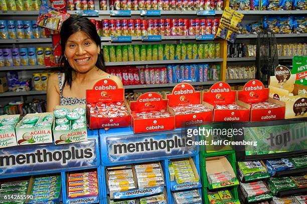 Sales clerk smiling at counter in a convenience store in Avenida San Juan.