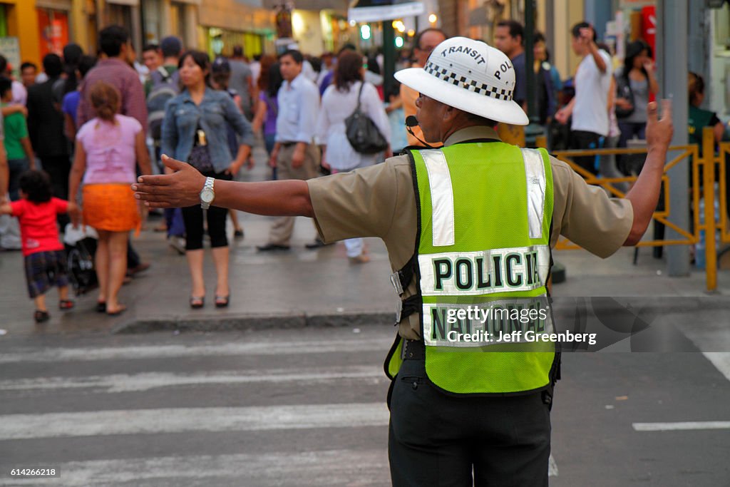 National police traffic cop helping people to cross the road of the historic district of Jiron de la Union.