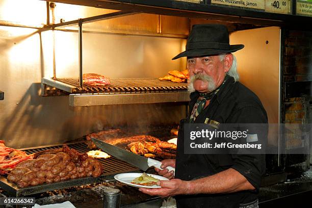 Man serving traditional food at the La Posada grill in the food court of Mendoza Plaza Shopping.