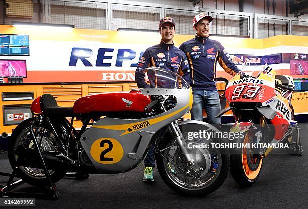 Repsol Honda Team's Spanish riders Dani Pedrosa and Marc Marquez pose beside 1966-67 Honda RC181 500-cc race motorcyle and current MotoGP race bike...