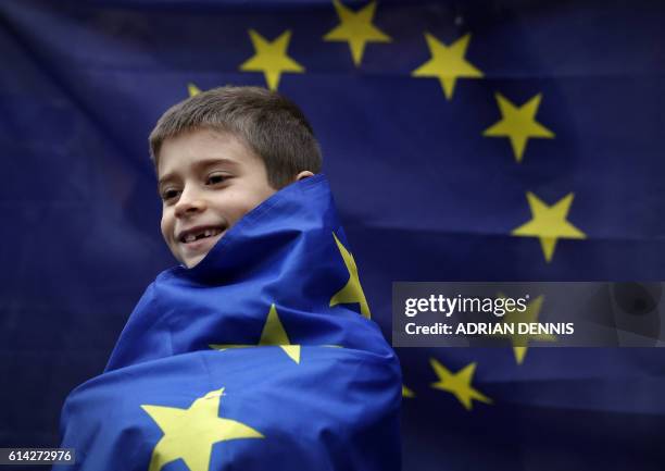 Young boy wrapped in a European Union flag stands outside The Royal Courts of Justice, Britain's High Court, in London on October 13 during a protest...