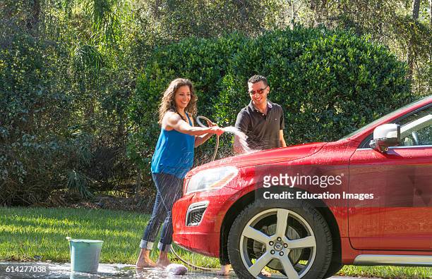 Couple wash car at home hispanic couple outside in sun red car fun together love Model Released, MR-12, MR-15.