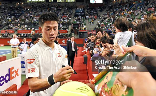 Kei Nishikori of Japan signs autographs for fans after his win in the men's singles first round match against Donald Young of USA on day one of...
