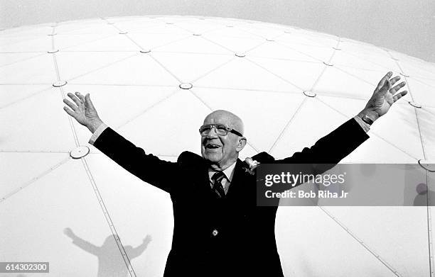 American architect, inventor, and futurist Buckminster Fuller raises his arms as he poses in front of a massive geodesic dome, Long Beach,...