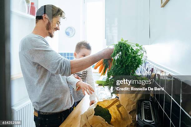 father and son organizing groceries in the kitchen - young man groceries kitchen stockfoto's en -beelden