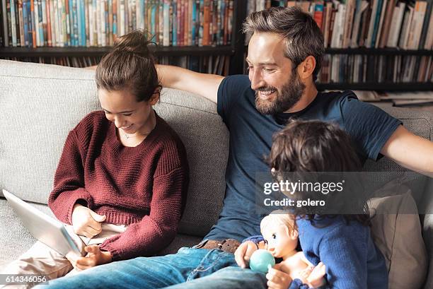 felice piccola famiglia sul divano guardando la tv su tablet computer - family with two children foto e immagini stock