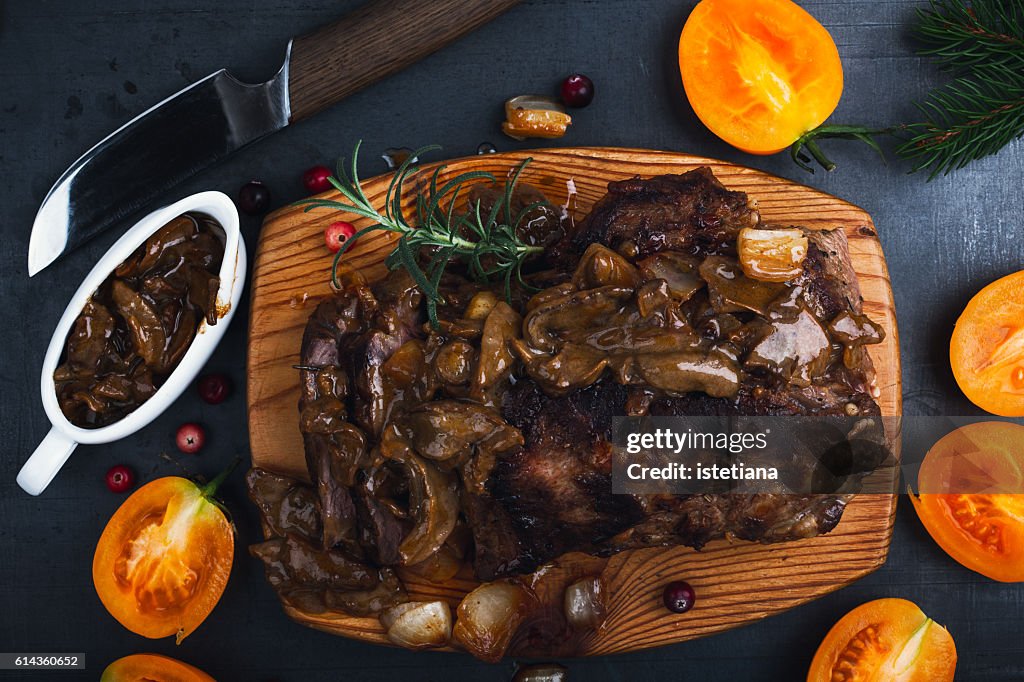 Roasted veal steak on board served with mushroom sauce viewed from above, Christmas dinner