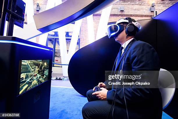 Man wears a PlayStation VR headset developed by Sony Interactive Entertainment LLC. To experience a 360-degree game in virtual reality, during a...