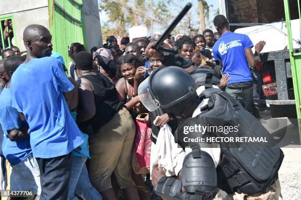 Haitian policeman pushes back Hurricane Matthew victims waiting for the delivery of food from the UN's World Food Programme in Tobeck, in Les Cayes,...