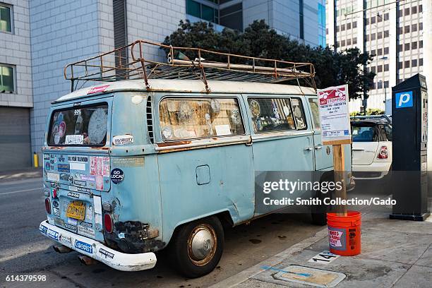 Beat up blue Volkswagen bus, covered in bumper stickers, parked along the street in the Tenderloin neighborhood of San Francisco, California, October...