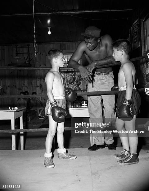 Floyd Patterson takes some time out of training to coach a couple of young boys at his training camp on May 12, 1956 at Greenwood Lake, New York.