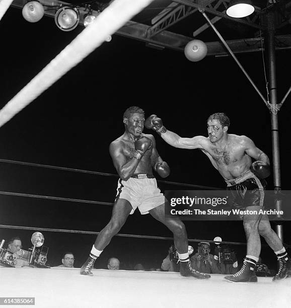 Rocky Marciano throws a right hook against Ezzard Charles during their bout at Yankee Stadium, on September 17,1954 in Bronx, New York. Rocky...