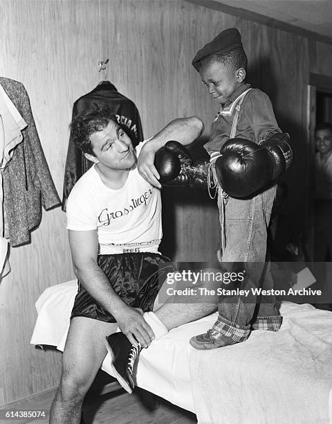 Rocky Marciano takes some time to entertain a young fan during his time training for his title defense against Archie Moore at Grossingers, New York,...