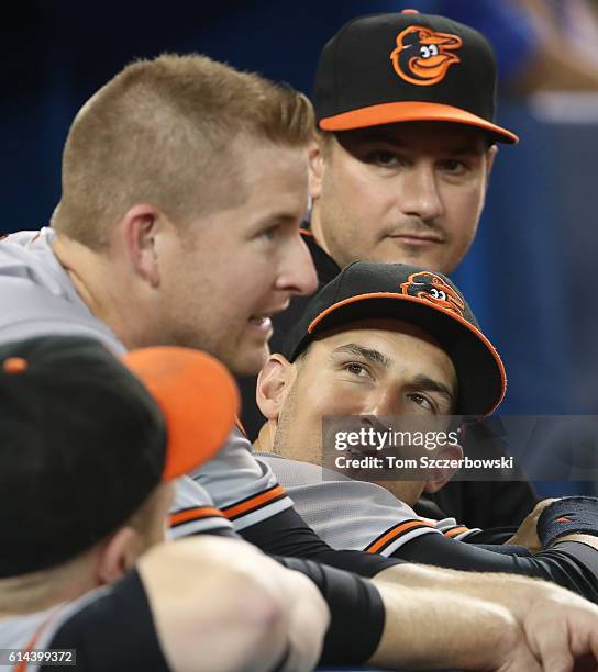 Ryan Flaherty of the Baltimore Orioles talks to Mark Trumbo on the top step of the dugout during MLB game action against the Toronto Blue Jays on...