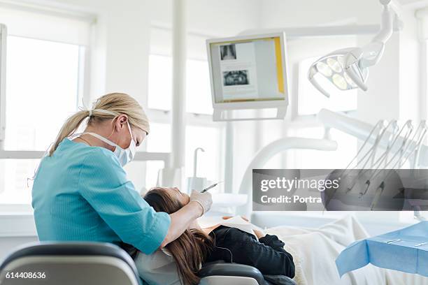 female dentist examining woman in clinic - dentist's chair stock pictures, royalty-free photos & images