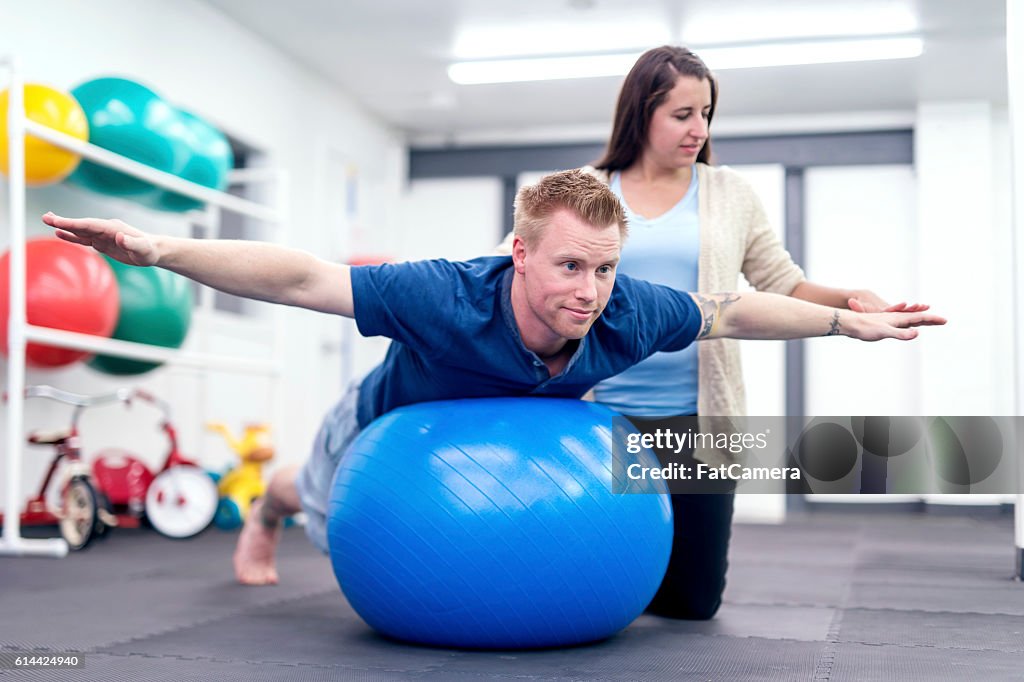 Adult male patient balancing on a therapy exercise ball