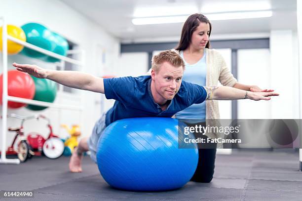 adult male patient balancing on a therapy exercise ball - post operation stock pictures, royalty-free photos & images