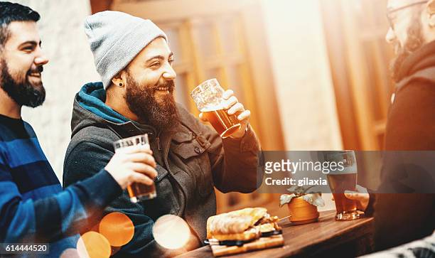 friends having beers at a pub. - bearded man stockfoto's en -beelden