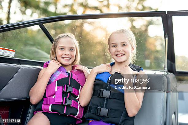 young female siblings smile while wearing lifejackets - life jacket stock pictures, royalty-free photos & images