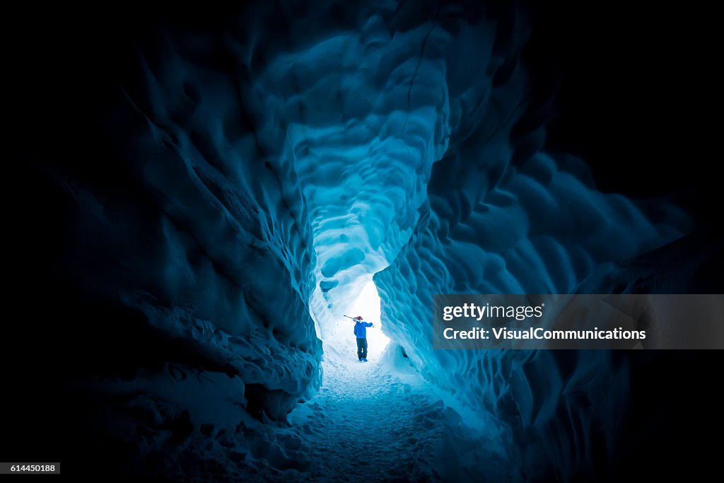 Skier exploring ice cave.