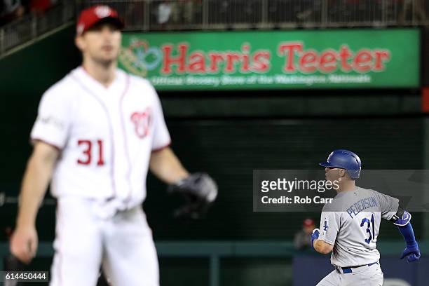 Joc Pederson of the Los Angeles Dodgers celebrates after hitting a solo home run in the seventh inning while Max Scherzer of the Washington Nationals...