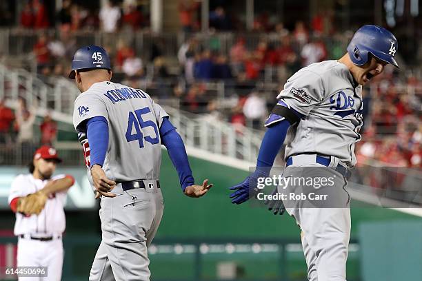 Joc Pederson of the Los Angeles Dodgers celebrates with third base coach Chris Woodward after hitting a solo home run in the seventh inning against...