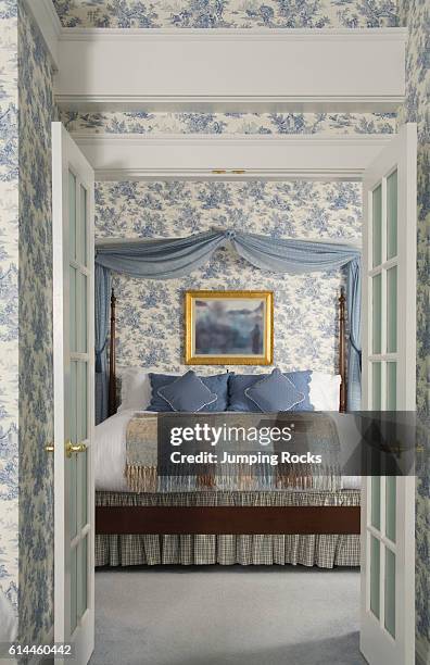 View through open double doors to bed with blue curtains above.