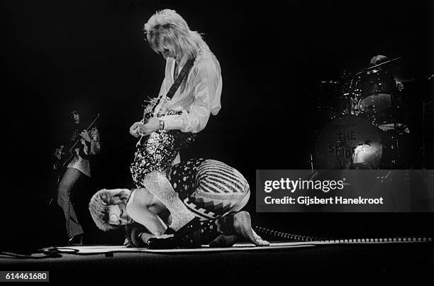 Guitarist Mick Ronson stands astride David Bowie as they perform on stage on the Ziggy Stardust tour, Earls Court Arena, London, 12th May 1973.