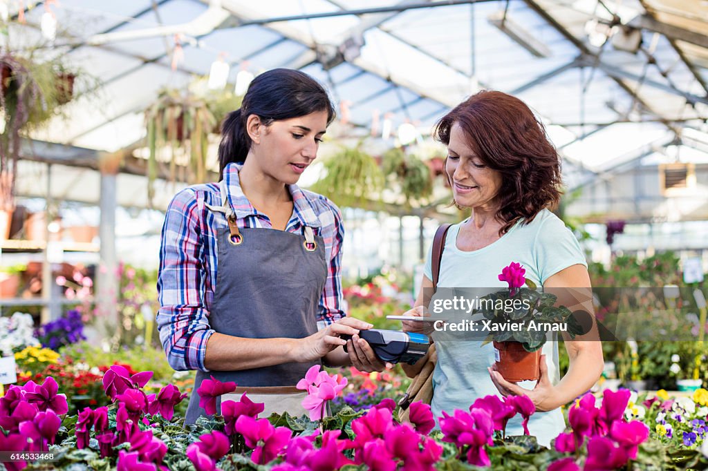 Mature customer making a contactless payment in garden center