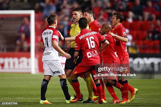 Referee Shaun Evans holds back Brendon Santalab of the Wanderers from Adelaide players after he made a hard tackle on James Holland of Adelaide...