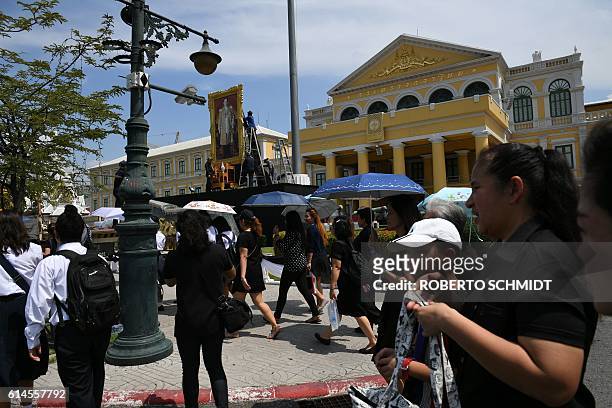 Thai people wanting to get a glimpse of the funeral caravan carrying Thai King Bhumibol Adulyadej, wear black clothes as they approach the vicinity...