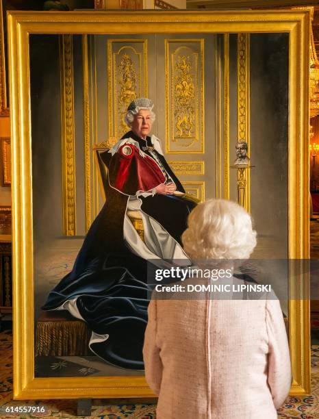 Britain's Queen Elizabeth II, views a painting of herself by British artist Henry Ward, at Windsor Castle in Windsor, west of London, on October 14,...