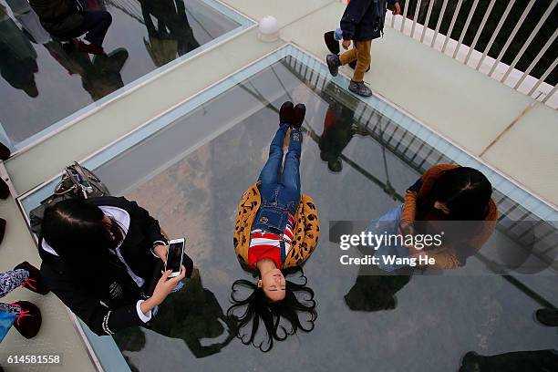 Yuong women pose for pictures on the glass-floor suspension bridge in Zhangjiajie in south China's Hunan province on October 14, 2016 in Zhangjiajie,...