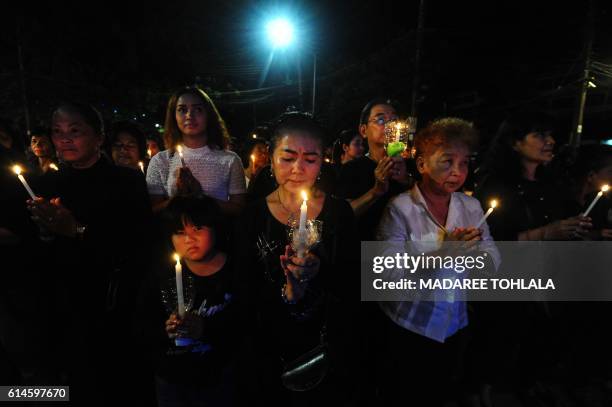 Mourners hold candles to pay respects to the late Thai King Bhumibol Adulyadej in the southern province of Narathiwat on October 14, 2016. - Massive...