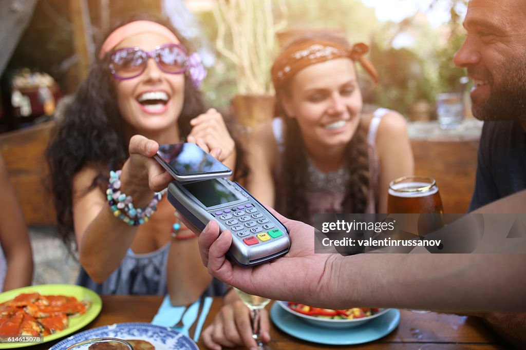 Cheerful young woman using smart phone for mobile payment