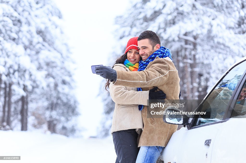Couple making selfie in front of a car in forest