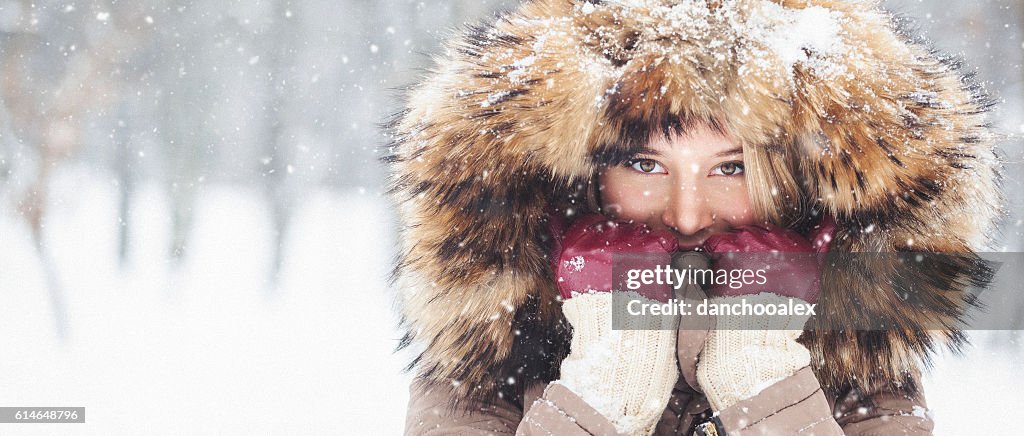 Jovem linda ao ar livre na neve com capuz