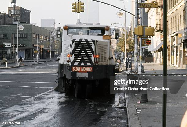 View a street sweeper at the intersection of 6th Avenue Waverly Place in Greenwich Village with the buildings of the Twin Towers of the World Trade...