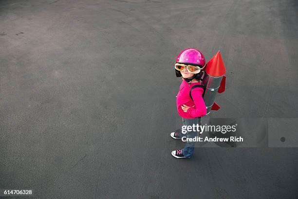 young girl dressed in a red rocket suit on blacktop - child discovering science stockfoto's en -beelden