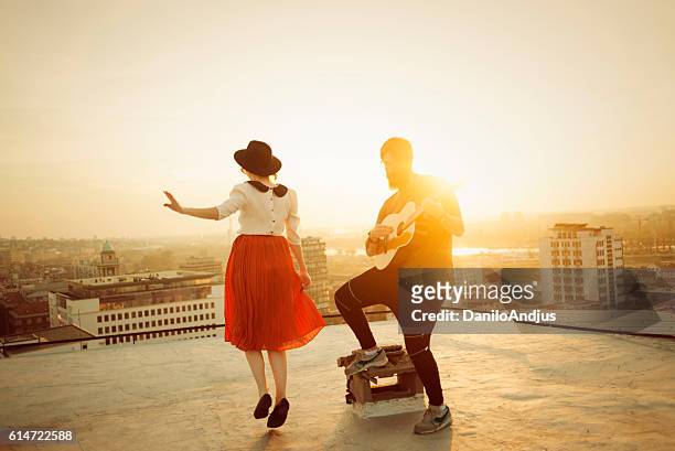 man playing the guitar and the woman dancing - singer songwriter stockfoto's en -beelden