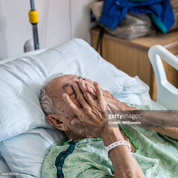 nervous elderly man hospital patient covering face with hands - hospital identification bracelet stock pictures, royalty-free photos & images