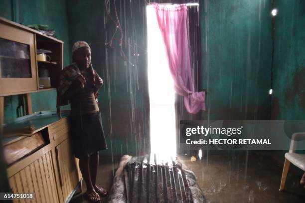 Judeline stands as the rain enters her house through the roof damaged by Hurricane Matthew, in Port-a-Pimet, Les Cayes, Haiti on October 14, 2016....