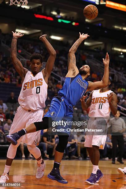 Deron Williams of the Dallas Mavericks attempts a shot past Marquese Chriss and Brandon Knight of the Phoenix Suns during the first half of the...