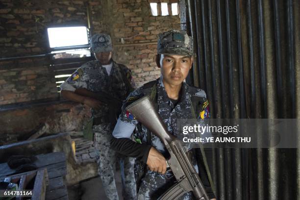 An armed Myanmar border police walk inside a building during a patrol in Maungni village in Maungdaw along the river dividing Myanmar and Bangladesh...